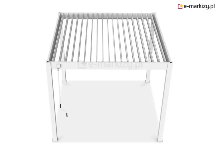 Zdjęcie prezentuje białą pergolę bioklimatyczną Marlo w ujęciu z góry, co pozwala na szczegółową ekspozycję mechanizmu dachu lamelowego. Aluminiowa, wolnostojąca konstrukcja oparta na czterech pionowych słupach o kwadratowym przekroju posiada dach wypełniony ruchomymi lamelami, które na fotografii są ustawione w pozycji otwartej (pionowej). Takie ustawienie piór umożliwia swobodną cyrkulację powietrza oraz regulację nasłonecznienia przestrzeni pod zadaszeniem. Na jednym z przednich słupów zamontowany jest manualny mechanizm korbowy z długim, białym drążkiem zakończonym czarnym uchwytem, służący do ręcznej zmiany kąta nachylenia lameli. Cała konstrukcja wykończona jest w matowej bieli, a stopy montażowe słupów posiadają kwadratowe maskownice, co nadaje całości estetyczny i nowoczesny wygląd.