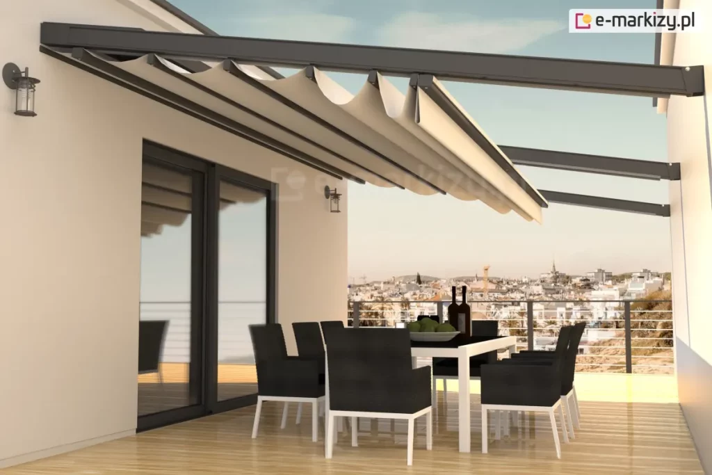 Nowoczesny dach tkaninowy rzymski Square zamontowany na przestronnym tarasie apartamentu. Konstrukcja zadaszenia opiera się na solidnych, aluminiowych profilach w kolorze antracytowym, które są przytwierdzone do elewacji budynku i wsparte na poprzecznych belkach. Jasnobeżowa, wodoodporna tkanina jest częściowo rozwinięta, tworząc charakterystyczne, głębokie fałdy podwieszone pod prowadnicami. Pod zadaszeniem znajduje się strefa jadalniana z dużym białym stołem oraz kompletem ośmiu nowoczesnych krzeseł w kolorze czarnym z białymi nogami. Taras wykończony jest jasnymi deskami kompozytowymi o wysokim połysku, w których odbijają się meble i elementy konstrukcyjne. W tle rozpościera się szeroka panorama miasta widoczna z dużej wysokości, ograniczona minimalistyczną balustradą ze stalowych linek. Na ścianie budynku, obok dużych przeszkleń, zamontowane są klasyczne kinkiety zewnętrzne, a całość oświetlona jest ciepłym światłem zachodzącego słońca, co podkreśla ekskluzywny charakter aranżacji.