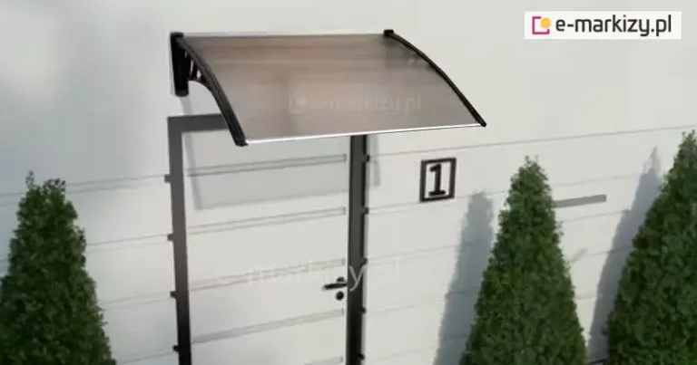 Grafika przedstawia wizualizację pojedynczego daszka drzwiowego model Coppoline, zamontowanego na białej, poziomo boniowanej elewacji nad jasnymi drzwiami wejściowymi. Konstrukcja zadaszenia składa się z dwóch czarnych wsporników o ozdobnym, ażurowym wypełnieniu z geometrycznymi motywami, które podtrzymują lekko nachyloną połaci wykonaną z poliwęglanu w odcieniu dymnego brązu. Płyta jest ujęta w ciemne profile boczne, a jej krawędź czołowa wykończona jest estetyczną listwą. Obok drzwi widoczna jest tabliczka z numerem posesji jeden, a całą aranżację uzupełniają symetrycznie ustawione przed budynkiem dwa wysokie, formowane krzewy iglaste w kształcie stożków. Daszek charakteryzuje się prostym, nowoczesnym designem, zapewniając ochronę strefy wejścia przed opadami atmosferycznymi przy zachowaniu dużej przepuszczalności światła.