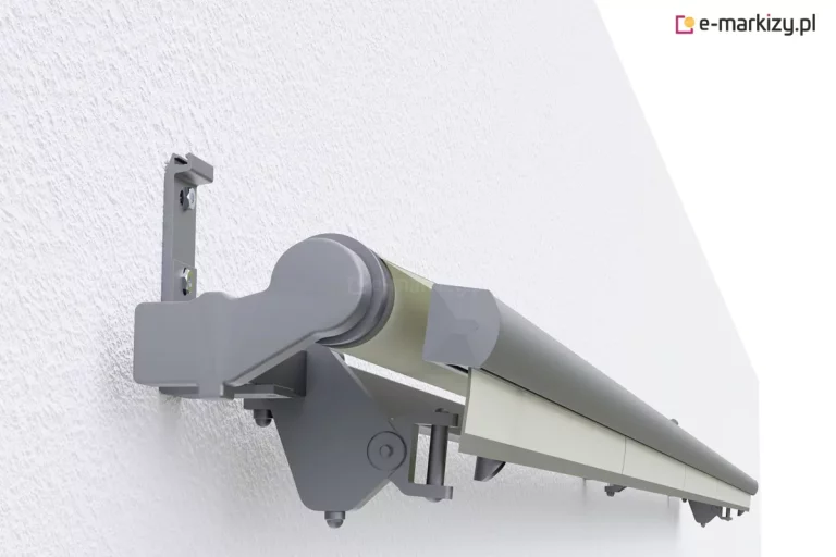 Trójwymiarowy model techniczny (render) bocznego mocowania i mechanizmu kasety markizy tarasowej zamontowanej na białej, otynkowanej ścianie. Widoczny jest aluminiowy uchwyt ścienny przykręcony dwiema śrubami, zintegrowany z masywnym wspornikiem bocznym w kolorze szarym (antracytowym). Mechanizm obejmuje półotwartą kasetę, w której znajduje się rura nawojowa z nawiniętą tkaniną w kolorze kremowym/beżowym. Poniżej kasety widoczny jest przegub ramienia składanego z widocznym sworzniem oraz elementami regulacji kąta nachylenia. Konstrukcja jest przedstawiona w perspektywie bocznej, ukazując detale spasowania elementów konstrukcyjnych oraz profil przedniej listwy dociążającej markizę.