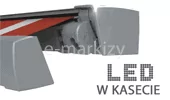 Grafika techniczna prezentująca opcję oświetlenia markizy tarasowej. Na jasnym tle widoczny jest profil boczny srebrzysto-szarej kasety markizowej w pozycji półotwartej. Z wnętrza kasety wysunięty jest fragment poszycia w biało-czerwone pasy oraz mechanizm ramienia przegubowego. W dolnej, prawej części grafiki umieszczono duży, stylizowany napis „LED” wykonany z drobnych kropek imitujących diody, a pod nim mniejszy napis drukowanymi literami „W KASECIE”. Całość ilustruje zintegrowany system oświetlenia diodowego, który jest montowany bezpośrednio w konstrukcji aluminiowej profilu markizy, zapewniając dodatkowe źródło światła pod rozwiniętym materiałem.