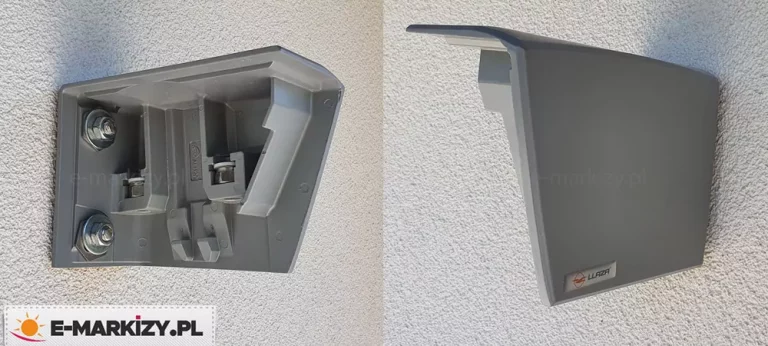 Zdjęcie przedstawia dwa ujęcia aluminiowego wspornika ściennego markizy tarasowej, zamontowanego na jasnej elewacji o strukturze baranka. Po lewej stronie widoczne jest wnętrze wspornika przymocowanego do ściany za pomocą dwóch solidnych śrub z podkładkami i nakrętkami, umieszczonych w pionowej osi elementu. Wewnętrzna konstrukcja wspornika posiada liczne żebrowania wzmacniające oraz specjalne gniazda i wypustki przeznaczone do stabilnego osadzenia mechanizmu markizy. Po prawej stronie znajduje się ujęcie tego samego wspornika z profilu, z założoną estetyczną osłoną maskującą w kolorze grafitowym. Osłona ma nowoczesny, lekko zaokrąglony kształt i całkowicie zakrywa elementy montażowe oraz wnętrze uchwytu, przylegając bezpośrednio do płaszczyzny ściany.