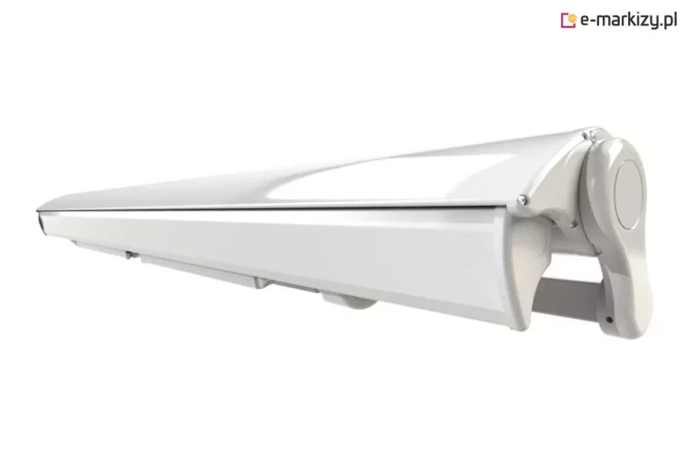 Zamknięta markiza tarasowa w pełnej kasecie aluminiowej, kolor biały, widok z boku na białym tle. Konstrukcja kasety: Całkowicie zamknięta, opływowa kaseta o przekroju aerodynamicznym, chroniąca tkaninę i ramiona przed czynnikami atmosferycznymi. Detale wykończenia: Widoczna boczna pokrywa kasety o zaokrąglonym kształcie z wyraźnym przetłoczeniem w formie koła. Belka frontowa markizy idealnie przylega do górnej części obudowy, tworząc szczelną i jednolitą bryłę. Elementy montażowe: Od spodu kasety widoczne są systemowe uchwyty mocujące oraz fragmenty konstrukcji nośnej, pozwalające na montaż ścienny lub sufitowy. Powierzchnia: Powłoka lakiernicza biała, błyszcząca, z widocznymi refleksami światła na górnej krawędzi obudowy. Perspektywa: Ujęcie pod kątem, ukazujące profil boczny oraz długość zamkniętego urządzenia, co podkreśla jego kompaktowy charakter po złożeniu.
