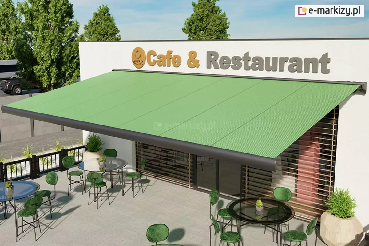 Parterowy budynek o jasnej fasadzie z dużym szyldem "Cafe & Restaurant" pod którym zamocowano markizę Palladio firmy Aluprof z konstrukcją o srebrzystografitowym kolorze oraz zieloną tkaniną poszycia. Markiza Tarasowa Palladio - Galeria Zdjęć nad restauracją zacienia wejście do restauracji, a pod nią rozstawiono stoliki z zielonymi krzesełkami. Ponad budynkiem widoczne drzewa oraz niebo.