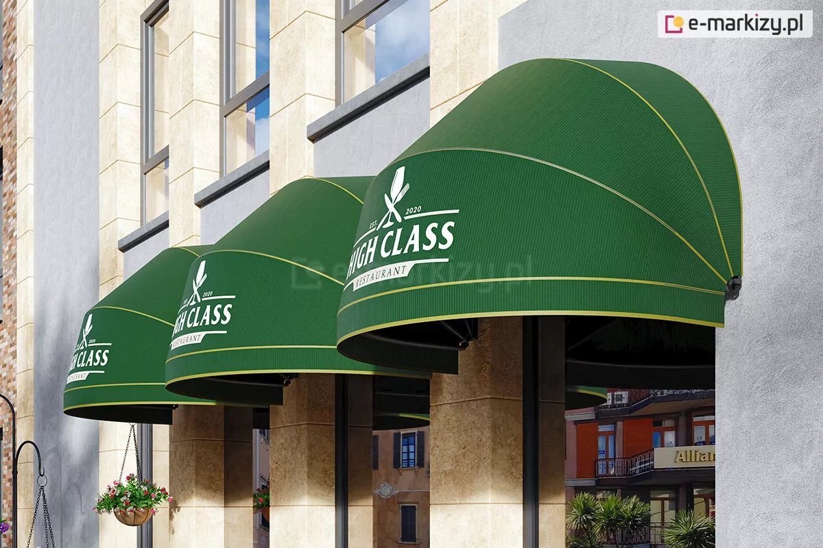 Zdjęcie prezentuje szereg trzech eleganckich markiz koszowych o półkolistym kształcie, zamontowanych nad wejściem do restauracji. Markizy wykonane są z tkaniny w głębokim, butelkowym odcieniu zieleni z delikatnym, pionowym prążkowaniem. Na froncie każdej z nich znajduje się białe logo z napisem "HIGH CLASS RESTAURANT" oraz symbolem skrzyżowanych sztućców i kieliszka. Dolna krawędź zadaszeń oraz szwy konstrukcyjne wykończone są subtelną lamówką w kolorze złotym lub jasnożółtym, co nadaje im prestiżowy wygląd. Zadaszenia są przymocowane do elewacji nowoczesnego budynku, która łączy gładkie, jasnoszare powierzchnie z piaskowymi filarami o teksturze naturalnego kamienia. Między filarami widoczne są duże przeszklenia witryn restauracyjnych. Po lewej stronie kadru, na tle elewacji, zwiesza się wiklinowa donica z drobnymi, różowymi i białymi kwiatami, zamocowana na czarnym, kutym łańcuchu. W tle, pod czaszami markiz, widać odbicie oraz fragmenty miejskiej zabudowy z budynkami o pomarańczowych i beżowych fasadach oraz zieloną roślinność. Światło słoneczne pada z góry, tworząc wyraźne cienie pod kopułami markiz i podkreślając trójwymiarowość ich formy.