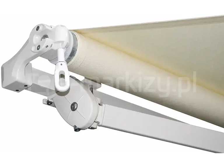 Detaliczne zdjęcie techniczne przedstawiające mechanizm zwijania boczny markizy tarasowej Piano Mol, zaprezentowane na czystym, białym tle. Konstrukcja oraz wszelkie elementy mechaniczne systemu zostały wykonane z aluminium lakierowanego proszkowo na kolor biały. W lewej części kadru widoczna jest przekładnia ślimakowa służąca do ręcznego sterowania osłoną, zakończona charakterystycznym, pionowym oczkiem na korbę. Przekładnia jest zintegrowana z uchwytem mocującym rurę nawojową, na którą nawinięte jest jasnobeżowe lub kremowe poszycie o wyraźnej strukturze tkaniny. Poniżej rury nawojowej znajduje się kwadratowa belka nośna, do której przymocowany jest uchwyt ramienia z przegubem obrotowym o zaokrąglonym kształcie, wzmocnionym poprzecznymi przetłoczeniami i śrubami montażowymi. Od przegubu odchodzi profilowane ramię przegubowe markizy, odpowiedzialne za napinanie materiału. Fotografia ukazuje detale konstrukcyjne od strony profilu bocznego, kładąc nacisk na spasowanie elementów mechanizmu sterującego i mocowania ramion.