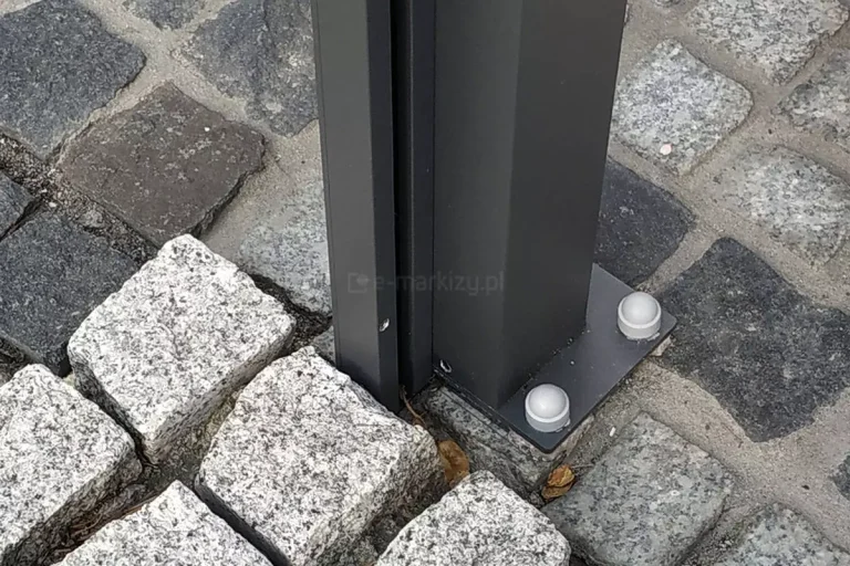 grafitowa podpora pergoli Dragon przymocowana do podłoża z kostki brukowej, do której dokręcony został profil prowadnicy do osłony bocznej - refleksola.