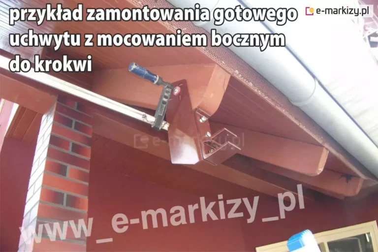 Pomalowana na brązowo podbitka dachu z widocznymi krokwiami, filarem wykończonym czerwono-brązową cegła oraz rynną widoczną ponad nią. Do jednej z krokwi przymocowany został uchwyt dachowy połączony z uchwytem ściennym do markizy Aluprof w kolorze brązowym. Powierzchnię uchwytu krokwiowego przymocowano do belki krokwi za pomocą ścisku, w celu zapewnienia idealnego dokręcenia jego powierzchni.