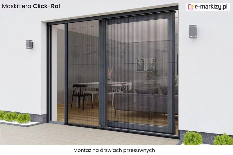 Prezentacja techniczna systemu ochrony przed owadami w postaci dwuskrzydłowej moskitiery plisowanej Click-Rol, która w całości zasłania otwór drzwiowy typu przesuwnego w nowoczesnym budynku mieszkalnym. Na fotografii widoczna jest pełna zabudowa siatką o strukturze harmonijkowej w kolorze ciemnoszarym, zintegrowana z aluminiową ramą konstrukcyjną w odcieniu antracytowym, idealnie wpasowującą się w otwór drzwi tarasowych. Dzięki zastosowaniu plisowanej siatki, bariera jest niemal przezierna, co pozwala na zachowanie wizualnego kontaktu z wnętrzem salonu, w którym widoczne jest współczesne wyposażenie, w tym stół jadalniany, tapicerowana sofa oraz jasna podłoga drewniana. Cały mechanizm został zamontowany w świetle muru białej elewacji, a jego konstrukcja cechuje się wysoką estetyką i dbałością o detale wykończeniowe, takie jak listwy prowadzące czy stabilne profile boczne. Zdjęcie ilustruje skuteczność systemu w zabezpieczeniu dużych przeszkleń przed insektami przy zachowaniu pełnej funkcjonalności drzwi przesuwnych, uzupełniając nowoczesną architekturę budynku o spójny wizualnie, praktyczny element wyposażenia zewnętrznego, podkreślony przez symetryczne oświetlenie elewacyjne i zadbaną roślinność ogrodową w dolnej części kadru.