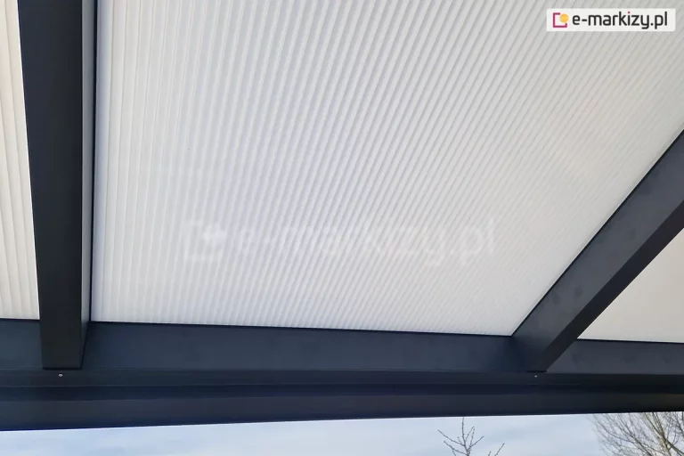 Zbliżenie na płytę z poliwęglanu komorowego w odcieniu mlecznym, zamocowaną w konstrukcji zadaszenia o antracytowym kolorze.
