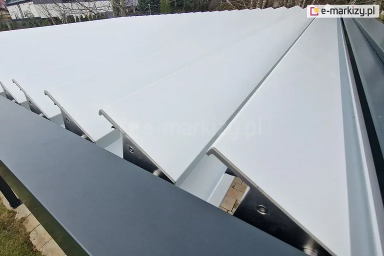 Zbliżenie na białe lamele dachu pergoli SB350 Aluprof zamocowane w antracytowej konstrukcji. Widoczne miejsce łączenia lameli z konstrukcją.