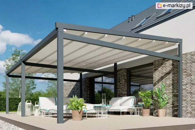 Nowoczesna pergola tarasowa Moderno, charakteryzująca się solidną konstrukcją z profili aluminiowych w kolorze antracytowym. Zadaszenie stanowi jasny, segmentowy materiał tkaninowy, który jest w pełni rozwinięty i zamontowany na prowadnicach pod lekkim kątem, co ułatwia odpływ wody. Konstrukcja przylega do elewacji budynku wykończonej jasną cegłą klinkierową z dużymi przeszkleniami. Na jasnym tarasie pod pergolą zaaranżowano strefę wypoczynkową z białymi sofami o błękitnych lamówkach, białymi stolikami kawowymi oraz roślinami w donicach, co tworzy spójną i elegancką przestrzeń rekreacyjną.