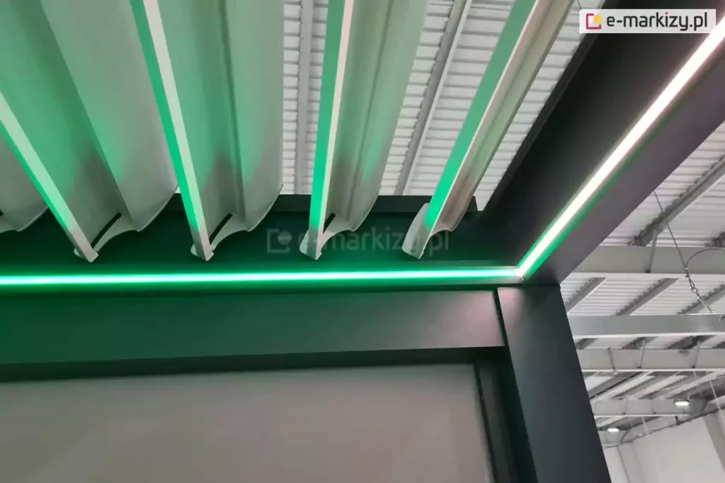 Pergola lamelowa z antracytową konstrukcją i białymi lamelami ze zintegrowanym oświetleniem LED w kolorze zielonym.