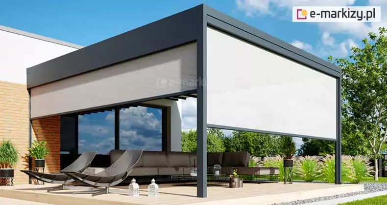 Wizualizacja nowoczesnej pergoli Luxury zamontowanej do elewacji budynku, przedstawiająca zaawansowany system osłon bocznych typu Refleksol. Konstrukcja pergoli wykonana jest z profili aluminiowych w kolorze ciemnego antracytu i posiada zintegrowane rolety tkaninowe w odcieniu jasnoszarym. Na zdjęciu widoczna jest pergola z częściowo opuszczoną przesłoną na boku lewym oraz niemal całkowicie rozwiniętą roletą na froncie, co zapewnia prywatność i ochronę przed słońcem w strefie wypoczynkowej. Pod zadaszeniem, na drewnianym tarasie, znajduje się szary narożnik oraz dwa designerskie, ciemne leżaki. Tło stanowi elewacja budynku łącząca biały tynk z cegłą dekoracyjną oraz zadbany ogród z zielonymi drzewami i krzewami. Całość prezentuje funkcjonalność pergoli Luxury jako kompletnego systemu zabudowy tarasu, pozwalającego na regulację dopływu światła i osłonę przed wiatrem przy zachowaniu nowoczesnej estetyki.