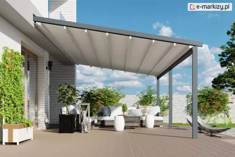 Grafika przedstawia wizualizację nowoczesnej pergoli przyściennej Luxo z w pełni rozwiniętym dachem tkaninowym w kolorze białym. Konstrukcja o minimalistycznym designie w kolorze ciemnego antracytu jest zamontowana do jasnej elewacji budynku wykonanej z białej cegły dekoracyjnej. Zadaszenie opiera się na dwóch solidnych słupach frontowych o kwadratowym przekroju, posadowionych na tarasie wyłożonym deskami kompozytowymi w jasnobrązowym odcieniu. Pod pergolą zaaranżowano strefę wypoczynkową z szarymi meblami ogrodowymi, białymi pufami oraz liczną roślinnością w dekoracyjnych donicach. W tle widoczny jest niski mur z jasnego kamienia, zielone krzewy oraz błękitne niebo z delikatnymi chmurami. Perspektywa ujęcia podkreśla dużą powierzchnię krycia zadaszenia oraz jego harmonijne dopasowanie do nowoczesnej architektury domu i ogrodu.