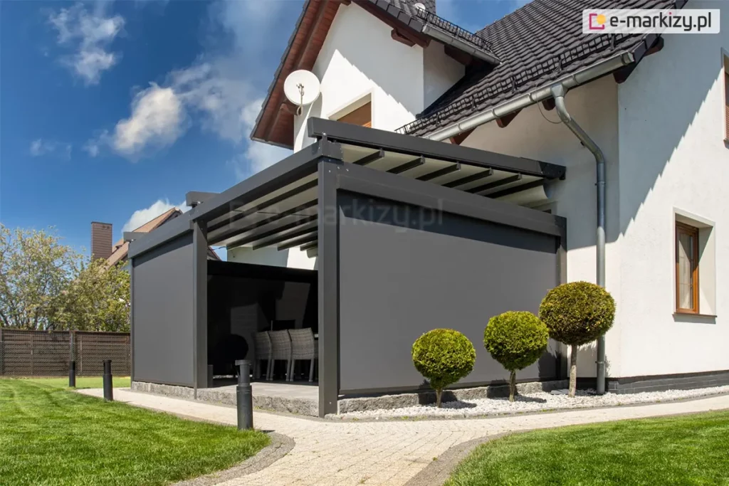 Przyścienna pergola tarasowa Solid z antracytowego aluminium z zamontowanymi do niej refleksolami Aluprof z boku i od frontu, które tworzą intymny zakątek na tarasie