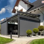 Przyścienna pergola tarasowa Solid z antracytowego aluminium z zamontowanymi do niej refleksolami Aluprof z boku i od frontu, które tworzą intymny zakątek na tarasie
