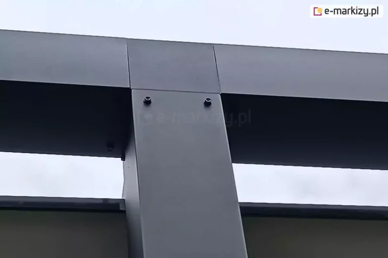 Fragment konstrukcji pergoli Tako z widocznym łączeniem słupa/podpory z trójnikiem. Wszystkie elementy konstrukcji wykonano w kolorze antracytowym, widoczne pozostają śruby łączące poszczególne elementy.