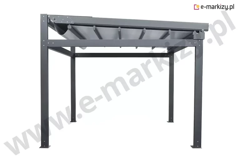 Widok z boku na wolnostojącą pergolę Solid Aluprof, prezentujący niemal całkowicie rozłożone zadaszenie tkaninowe oraz detale konstrukcyjne systemu przesuwnego. Aluminiowy stelaż w kolorze ciemnego grafitu tworzy sztywną ramę opartą na pionowych słupach o kwadratowym przekroju, na których widoczne są punktowe śruby montażowe. Jasnoszara tkanina techniczna jest rozpięta pod prowadnicami bocznymi, wsparta na szeregu poprzecznych profili aluminiowych, które zapewniają stabilność poszycia i zapobiegają jego trzepotaniu na wietrze. W tylnej części konstrukcji, po lewej stronie, materiał tworzy charakterystyczną, głęboką fałdę przy mechanizmie nawojowym, który od góry osłonięty jest systemowym daszkiem aluminiowym. Ujęcie to dokładnie obrazuje liniowość prowadnic oraz sposób, w jaki ruchome elementy dachu rzymskiego integrują się z masywną ramą obwodową pergoli. Całość przedstawiona jest na białym tle, co podkreśla techniczny charakter produktu oraz precyzję wykonania elementów wykończeniowych, takich jak boczne płyty maskujące z wielopunktowym mocowaniem.