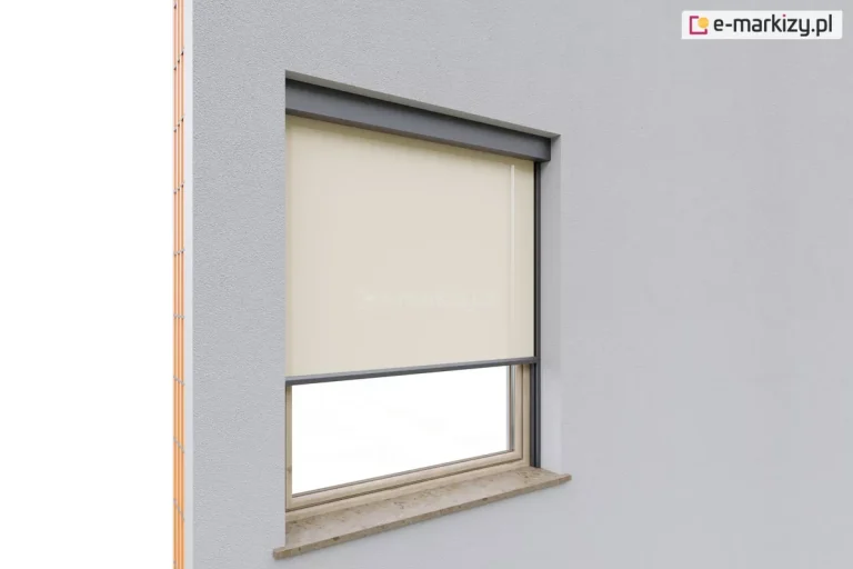 Refleksol 120 w wersji z prowadnicami bocznymi ościeznicowymi, które przykręcone zostały bezpośrednio do ramy okiennej. Tkanina zacieniająca w jasnym kolorze beżowym porusza się pionowo wzdłuż prowadnic z aluminium, zapewniając osłonę przeciwsłoneczną. System Aluprof zamontowany do elewacji z tynku cienkowarstwowego. Dolna część okna pozostaje odsłonięta, umożliwiając doświetlenie wnętrza. Rama okna z naturalnego drewna, z poziomym parapetem kamiennym i typową wnęką montażową. Po lewej stronie widoczna część ściany w trakcie budowy.