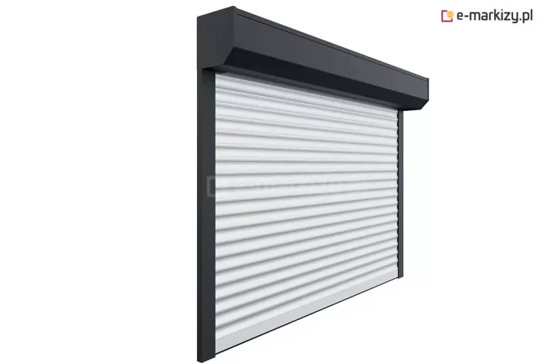 Zdjęcie przedstawia roletę zewnętrzną wykonaną na wymiar, dopasowaną idealnie do wnęki okiennej. Widoczna aluminiowa kaseta w wersji natynkowej mieści zwijany pancerz rolety, który porusza się w bocznych prowadnicach. System zapewnia estetyczne wykończenie elewacji, a także ochronę przeciwsłoneczną, termiczną i prywatność. Roleta może być wyposażona w napęd ręczny lub elektryczny, w zależności od preferencji użytkownika.