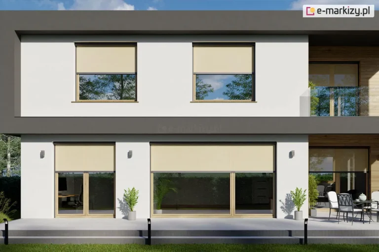 Zdjęcie prezentuje nowoczesny, dwukondygnacyjny budynek mieszkalny o minimalistycznej architekturze i jasnej elewacji, wyposażony w system zewnętrznych rolet typu screen w kolorze jasnego beżu. W górnej kondygnacji budynku znajdują się dwa symetrycznie umieszczone okna z drewnianymi ramami, częściowo zasłonięte roletami, w których widocznym odbiciu maluje się błękitne niebo z chmurami oraz korony drzew. Po prawej stronie piętra zaprojektowano otwarty taras z przeszkloną balustradą i widocznym segmentem drewnianej okładziny ściennej. Na parterze ulokowano duże, panoramiczne przeszklenia z widocznym wyjściem na przestronny, jasnoszary taras wyłożony płytami betonowymi, na którym rozmieszczono dekoracyjne rośliny w donicach oraz nowoczesny zestaw wypoczynkowy ze stołem i krzesłami ogrodowymi. Oknom i drzwiom tarasowym na parterze również towarzyszą zamontowane w górnych częściach kasety rolet screen, częściowo zacieniające wnętrza i redukujące wpadające promienie słoneczne. Bryłę budynku domyka ciemnoszara, grafitowa rama stropowa oraz attyka, tworząc wyrazisty kontrast z jasnymi ścianami. Wzdłuż tarasu widoczne są czarne, minimalistyczne oprawy oświetleniowe gruntowe, a przed budynkiem rozciąga się równo przycięty pas zielonego trawnika w pełnym świetle słonecznym.