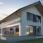 Biała aluminiowa pergola tarasowa Tarasola Light zamontowana przy nowoczesnym, piętrowym domu jednorodzinnym o jasnej elewacji i dwuspadowym dachu. Konstrukcja pergoli charakteryzuje się minimalistycznym designem i jest wyposażona w zintegrowane oświetlenie punktowe LED rozmieszczone na poprzecznych profilach podtrzymujących białe, tkaninowe poszycie dachu. Zadaszenie jest lekko nachylone, co umożliwia swobodny odpływ wody opadowej, i przylega bezpośrednio do bocznej ściany budynku. Pod pergolą, na drewnianym tarasie, znajduje się zestaw mebli ogrodowych składający się z dużego prostokątnego stołu oraz sześciu nowoczesnych krzeseł z ciemnoszarym obiciem. Taras jest wyniesiony ponad poziom trawnika i wykończony podświetlanym stopniem u podstawy. W tle widoczny jest ogród z młodymi drzewami bez liści oraz sąsiednie zabudowania, a cała scena przedstawiona jest w chłodnym, wieczornym świetle z wyraźnie rozświetlonym wnętrzem domu przez duże przeszklenia i drzwi tarasowe.