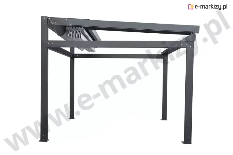 Widok ogólny wolnostojącej pergoli tarasowej Solid Aluprof prezentujący konstrukcję w kolorze ciemnego antracytu z częściowo zwiniętym poszyciem dachowym. Aluminiowy stelaż składa się z czterech pionowych słupów o kwadratowym przekroju, które u podstawy posiadają płaskie stopy montażowe z fabrycznymi wycięciami na kotwy. Górna część budowli to masywna rama obwodowa zintegrowana z bocznymi prowadnicami, w których porusza się system dachu rzymskiego. Jasna, techniczna tkanina zadaszenia jest w tym momencie złożona w tylnej części konstrukcji, tworząc regularne, poziome fałdy materiału podwieszone pod szynami jezdnymi. Tylna belka została wyposażona w systemowy daszek ochronny wystający powyżej linii ramy, który zabezpiecza zwinięty pakiet poszycia przed opadami i zanieczyszczeniami. Całość konstrukcji charakteryzuje się nowoczesną, kubistyczną formą o matowym wykończeniu, z precyzyjnie spasowanymi narożnikami i brakiem widocznych na zewnątrz elementów mechanicznych, co podkreśla techniczny minimalizm produktu.