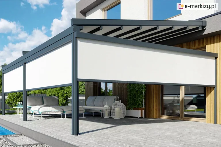 Aluminiowa pergola tarasowa w kolorze ciemnego antracytu, zamontowana do elewacji nowoczesnego budynku mieszkalnego, charakteryzującego się połączeniem bieli oraz pionowych paneli o strukturze jasnego drewna. Konstrukcja zadaszenia opiera się na trzech solidnych, pionowych słupach o kwadratowym przekroju, ustawionych na jasnoszarym, betonowym podłożu tarasu. Górna część pergoli posiada ruchome poszycie tkaninowe w formie jasnych pasów, które są rozpięte pomiędzy belkami przeciwwietrznymi. Frontowa oraz boczna strona pergoli zostały wyposażone w pionowe osłony typu screen (refleksol Zip L Zip U), z tkaniną screen w kolorze białym, które są częściowo rozwinięte, zasłaniając górną połowę przestrzeni między słupami i tworząc barierę przed słońcem. Pod zadaszeniem znajduje się przestronna strefa wypoczynkowa z nowoczesnymi meblami ogrodowymi, w tym niskimi sofami z grubymi, jasnoszarymi poduchami oraz białymi ażurowymi lampionami dekoracyjnymi. W tle widoczne są duże przeszklenia okienne, w których odbija się błękitne niebo z białymi chmurami. Po lewej stronie kadru znajduje się fragment basenu z błękitną wodą, oddzielony od tarasu pasem drobnego, szarego żwiru. Całość kompozycji dopełnia niska roślinność w donicach oraz soczysta zieleń drzew widoczna w tle posesji.
