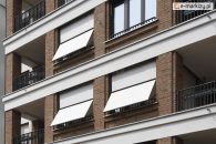 Jasne rolety balkonowe na ceglanej fasadzie