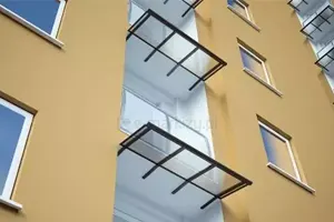 Duże daszki osłaniające balkony w nowoczesnym bloku na solidnych uchwytach sufitowych