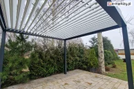 Pergola ogrodowa do samodzielnego montażu zamontowana w ogrodzie z cyprysami
