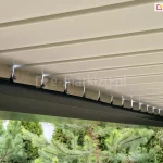 Pergola ogrodowa metalowa ze złożonym dachem z białych lameli i rynną w kolorze antracytowym