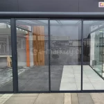 Zamknięte, przesuwne drzwi szklane Sotro z solidną, aluminiową ramą w kolorze antracytowym, przeznaczone do zadaszenia pergoli lub tarasu. Zdjęcie prezentuje elegancką i nowoczesną stylistykę konstrukcji.