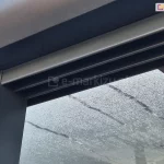 Górna prowadnica systemu szklanego Sotro z trzema torami zlicowanymi z antracytową podporą pergoli tarasowej.