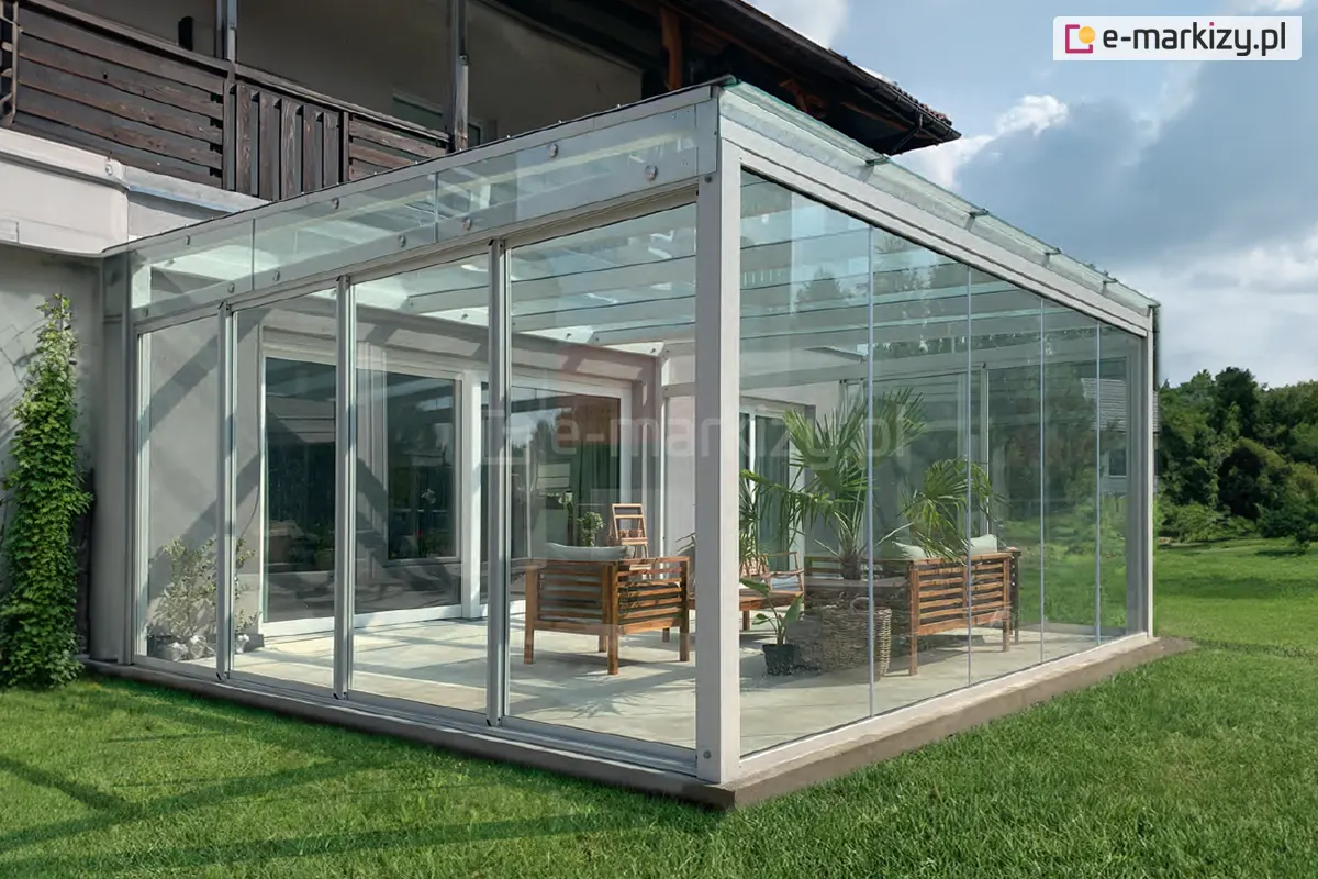 Nowoczesna szklana pergola ogrodowa z zabudową systemem ramowych drzwi przesuwnych Sotro, w lekkiej aluminiowej konstrukcji z przeszklonym dachem i drewnianymi meblami wewnątrz.