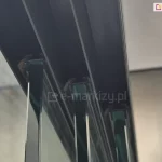 Zielonkawe panele szklane Miros na górnej prowadnicy trzytorowej, ukazujące detal montażu w zabudowie tarasowej z pergolą