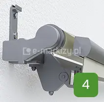 Uchwyt ścienny i boczna obudowa markizy Australia Selt w kolorze szarym, zamontowane do elewacji budynku, widoczne elementy mocujące i uchwyt montażowy