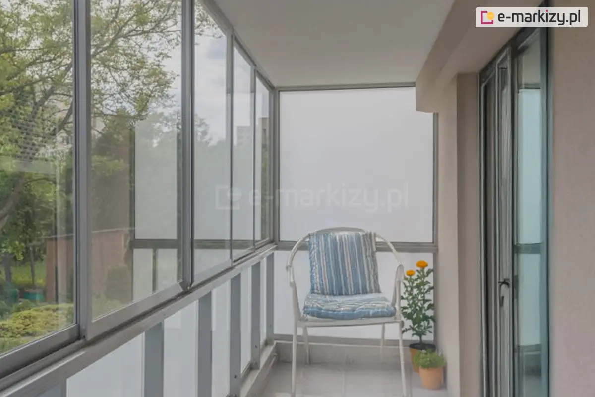 Zabudowany balkon z przesuwnymi szybami systemu Sotro, z krzesłem i rośliną doniczkową.