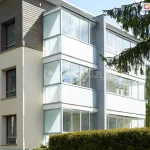 Zabudowane balkony w bloku mieszkalnym z zastosowaniem przeszkleń przesuwnych Sotro – estetyczne i funkcjonalne osłony szklane w kolorze dostosowanym do elewacji bloku.