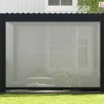 Zewnętrzna roleta typu screen zamontowana na froncie pergoli Gloria. Efektywna ochrona przeciwsłoneczna z przewiewną tkaniną.