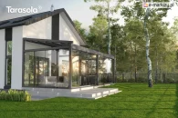 Pergola Elegancy Tarasola przekształcona w całoroczną zabudowę tarasu dzięki pełnym przeszkleniom tworzy jasną, nowoczesną przestrzeń wypoczynkową. Przesuwne szklane panele otwierają widok na ogród z drzewami i dużym, zadbanym trawnikiem.