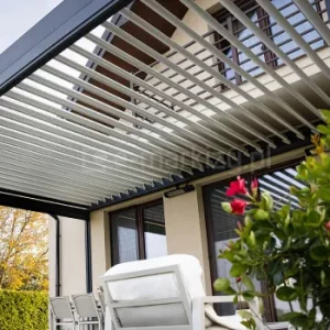 Lamelowy dach Tarasola Essential, pokazany z dołu, z równymi, obracanymi aluminiowymi piórami tworzącymi jasną, elegancką konstrukcję nad tarasem; w tle widoczna część domu i rośliny wprowadzające naturalny, przytulny klimat.