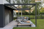 Automatyczna pergola tarasowa Square Flat z aluminiową konstrukcją w kolorze antracytowym i zwiniętą tkaniną dachową schowaną pod daszkiem, zamontowana przy elewacji domu z żaluzjami fasadowymi, wyposażona w narożną sofę i leżaki z poduszkami, ustawione na przestronnym tarasie z płyt gresowych otoczonym zielonym trawnikiem.