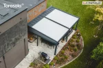 Wolnostojąca podwójna pergola Elegancy Tarasola z dużym tkaninowym dachem ustawiona obok budynku, zapewnia obszerną przestrzeń wypoczynkową z sofami i stołem na eleganckim tarasie. Widok z góry ukazuje jej skalę i dopasowanie do ogrodu z bujną roślinnością oraz geometrycznymi rabatami.