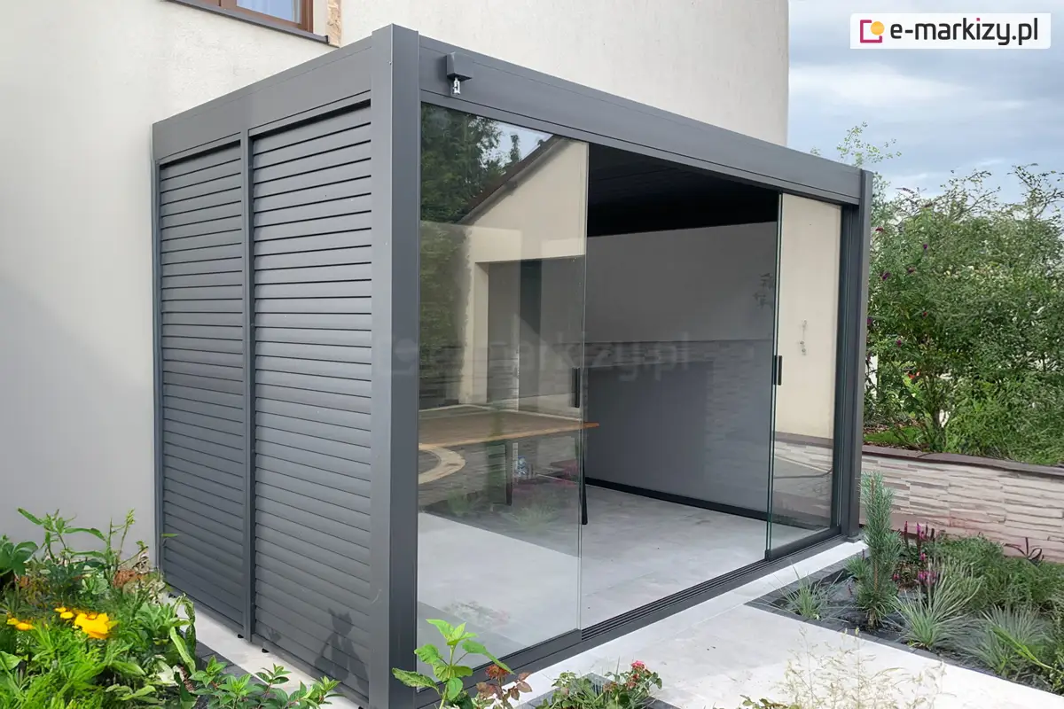 Frontowe drzwi szklane do pergoli Marlo Rubio zamontowane przy nowoczesnym domu jednorodzinnym w komplecie z żaluzjami fasadowymi po boku