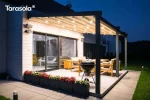 Pergola Elegancy Tarasola prezentuje system LED rozmieszczony w dachu tkaninowym, który podkreśla nowoczesny styl zadaszenia tarasowego. Oświetlona konstrukcja otacza strefę wypoczynku z drewnianymi meblami, a tło stanowi przestronny trawnik.