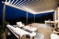 Pergola Essential Tarasola posiada dach z obróconymi lamelami, które wieczorem tworzą nastrojową iluminację LED. Jasne światło podkreśla elegancję konstrukcji i nadaje tarasowi domowemu przytulny charakter, tworząc idealne miejsce na wieczorne spotkania.