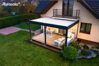 Elegancka konstrukcja Essential z obracanymi lamelami ułożonymi prostopadle do ściany budynku. Na ujęciu z góry widać spójną kolorystykę antracytowej ramy oraz jasnych lameli, a poniżej taras z ogrodem harmonijnie komponuje się z bryłą domu.