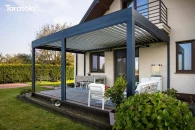 Aluminiowa pergola tarasowa Essential z otwartymi lamelami dachowymi osłaniająca wygodny taras z zestawem wypoczynkowym wśród zieleni ogrodu